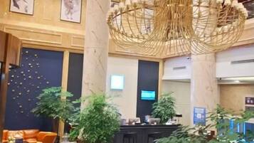 A lobby with a reception desk, seating area, and decorative plants.