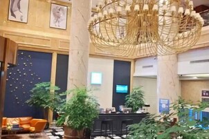 Un vestíbulo con mostrador de recepción, zona de estar y plantas decorativas.