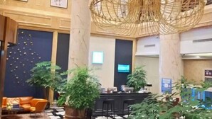 Un hall con mostrador de recepción, zona de estar y una gran lámpara decorativa.