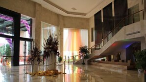 A spacious lobby with a polished floor, a staircase, and a large window with a colorful view. - Beiliu International Hotel (Beiliu)