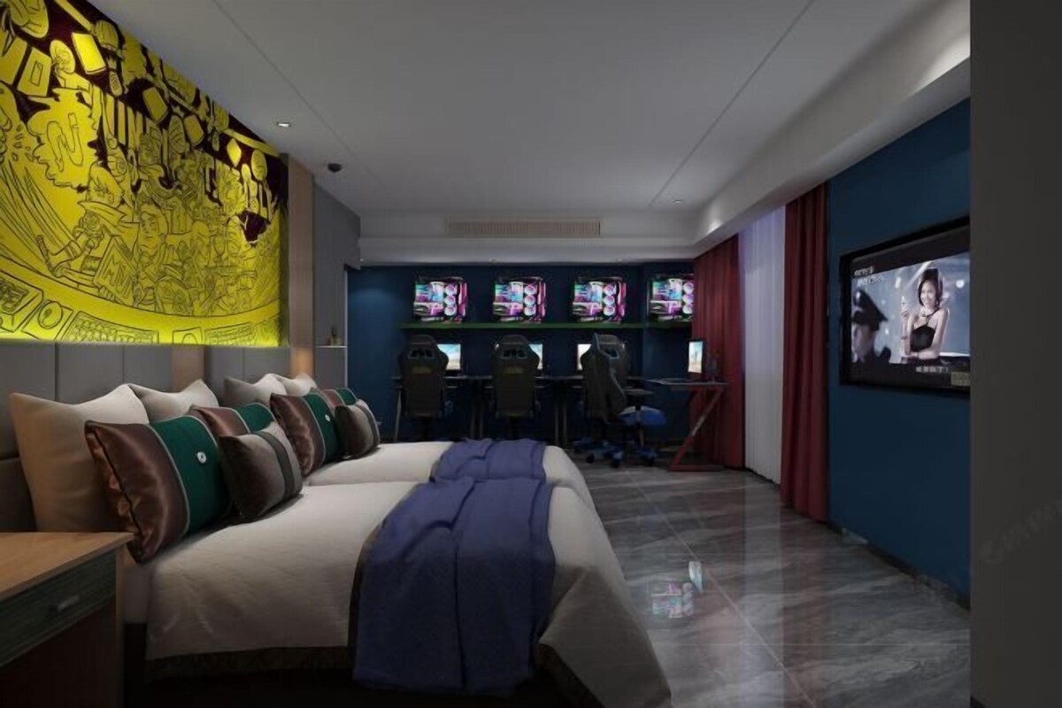 Une chambre d’hôtel avec un grand lit, un bureau doté de plusieurs écrans et un téléviseur.