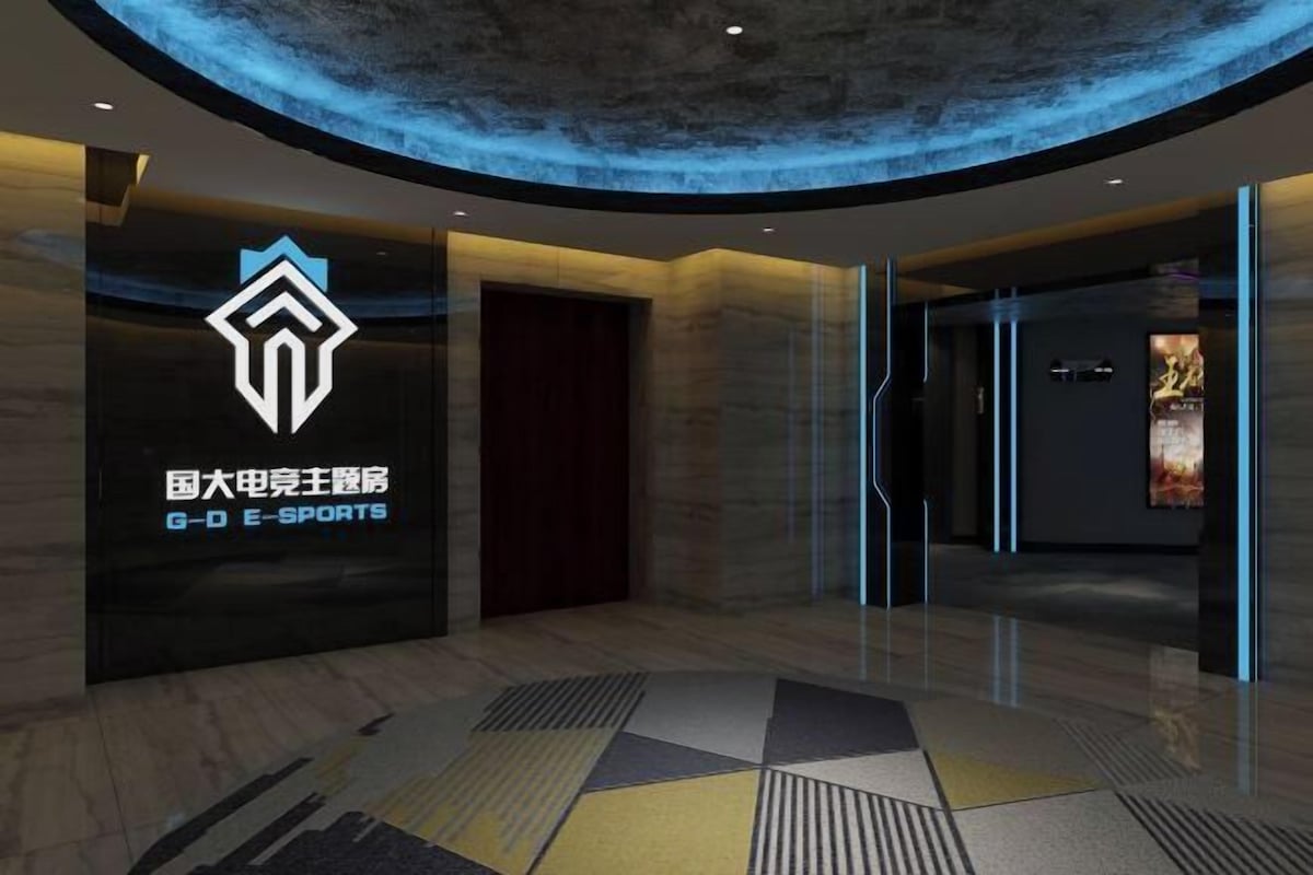 A modern lobby with a geometric patterned floor, a prominent logo on the wall, and a curved ceiling design.
