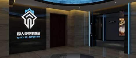 A modern lobby with a geometric patterned floor, a prominent logo on the wall, and a curved ceiling design.