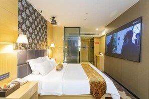 Quarto de hotel com uma cama, televisão, escrivaninha e mesa de cabeceira.