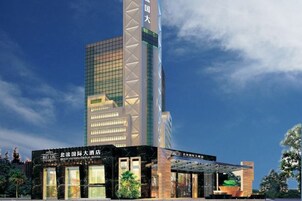 Un moderno edificio de hotel con una estructura vertical destacada y una entrada de techo plano.