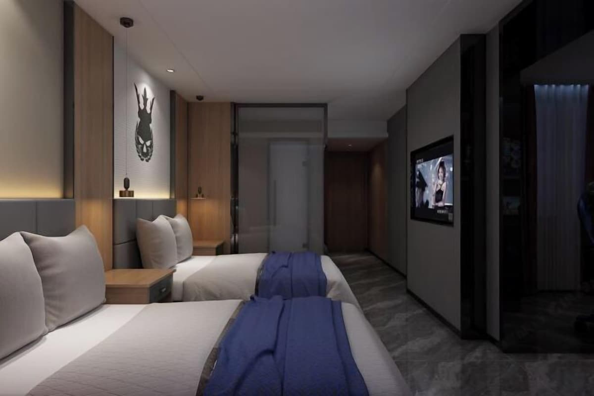 A modern hotel room with two beds, a large TV screen, and a wall-mounted artwork.