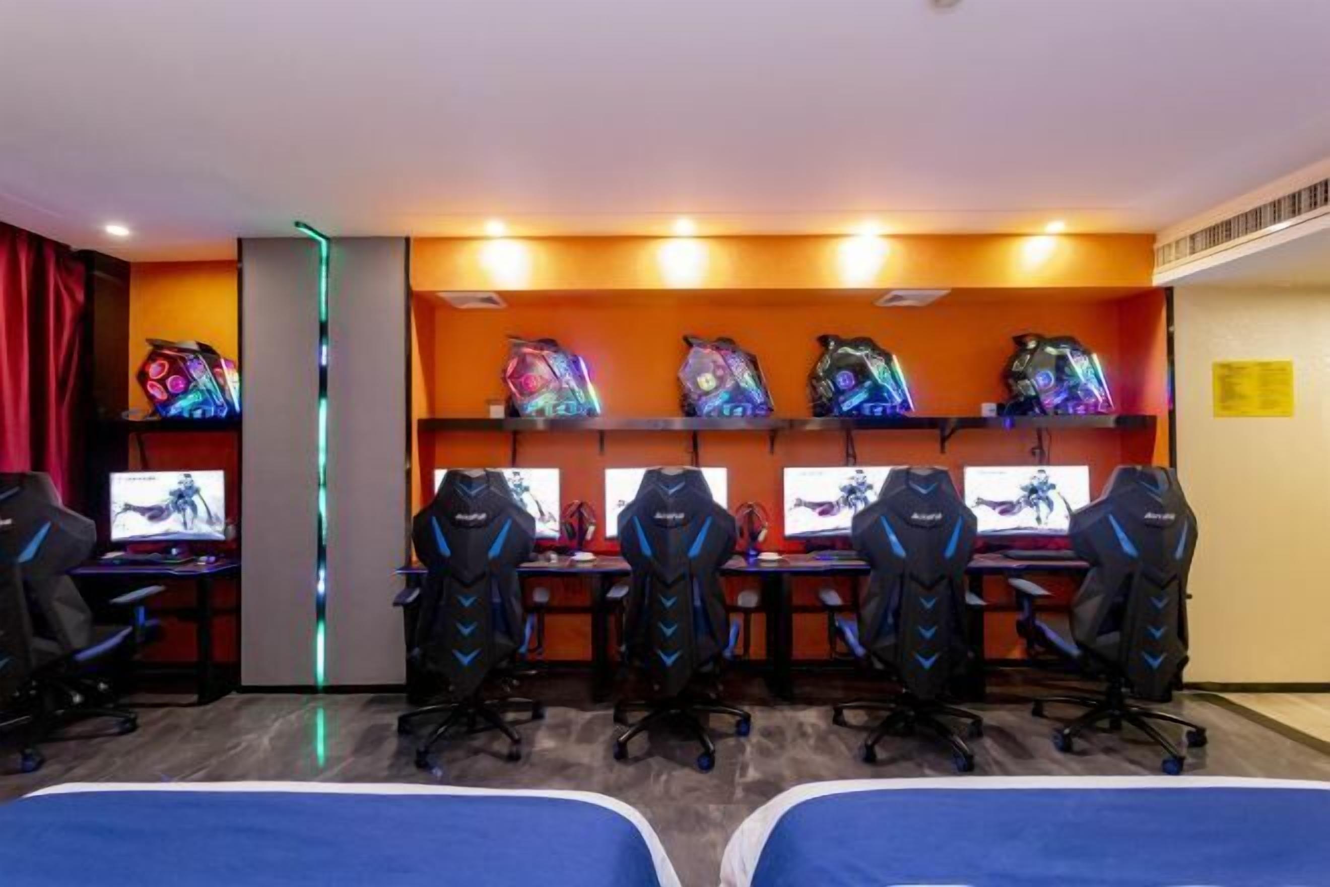Una sala de juegos con varias sillas, escritorios y monitores.