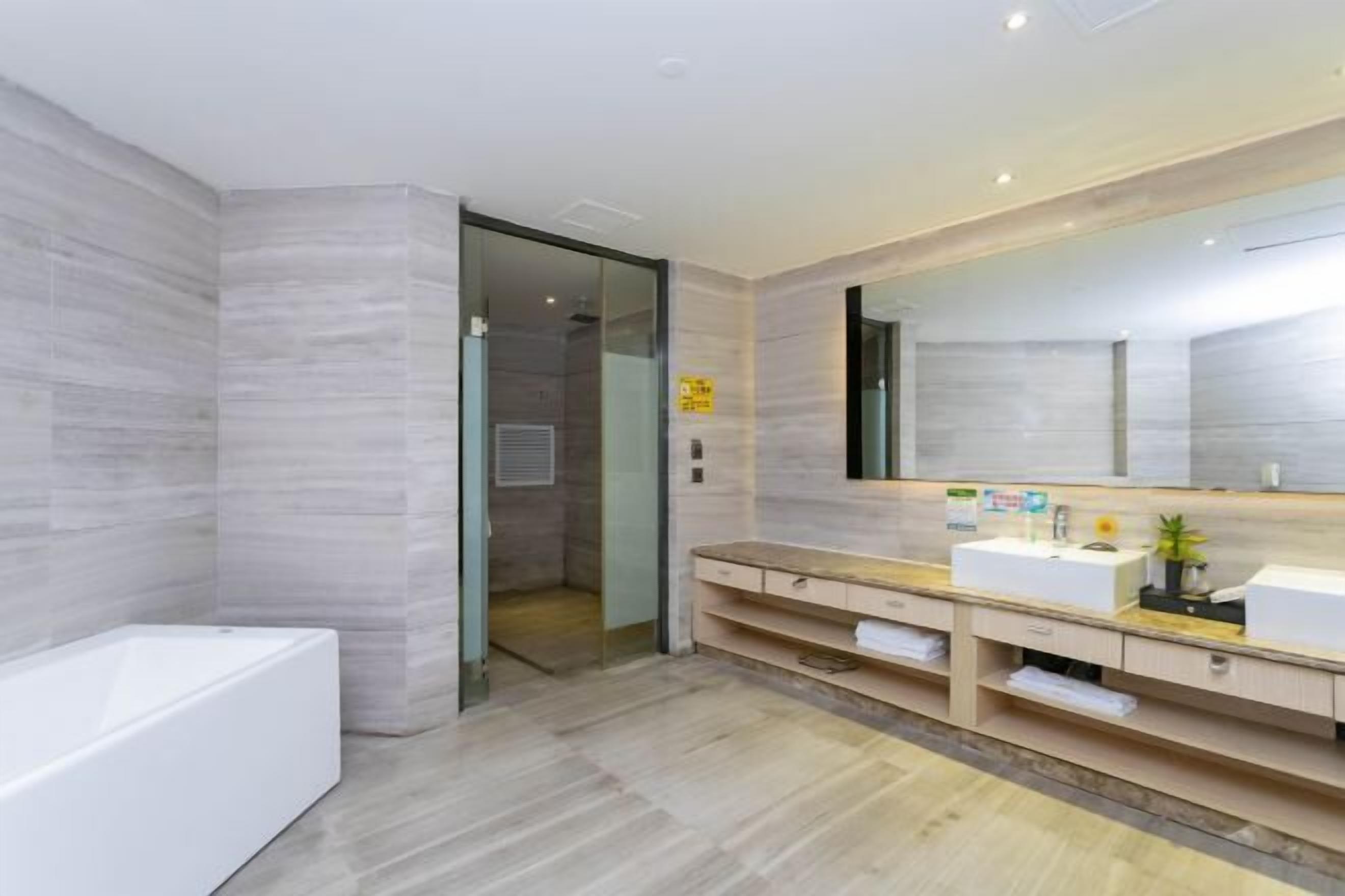 Un baño moderno con una bañera grande, un tocador con espejo y una zona de ducha.
