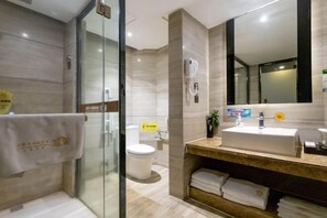 A modern bathroom with a glass shower enclosure, a sink with a mirror, and a toilet. - Beiliu International Hotel (Beiliu)