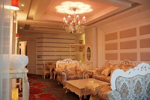 Una habitación con candelabro, un conjunto de sofás, una mesa de comedor con sillas y un espejo.