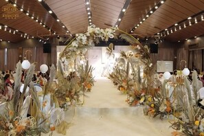 Un espai interior amb una fornícula floral, un escenari i una zona de seients.