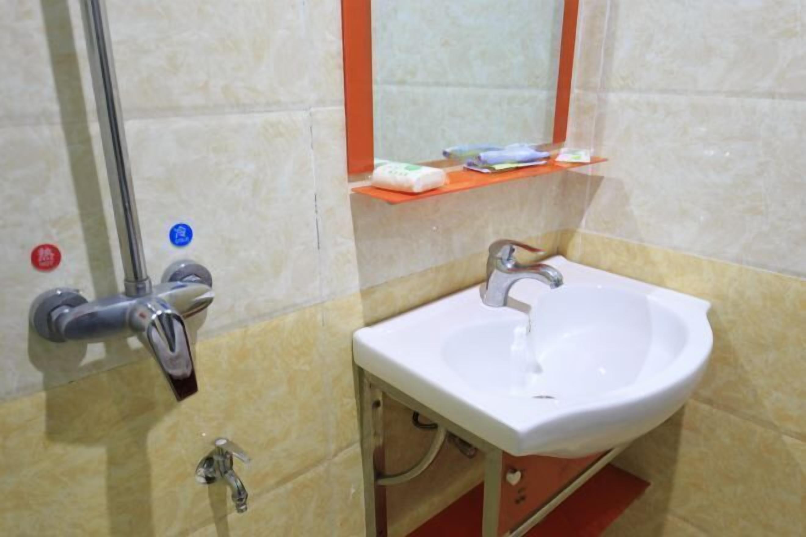 Un baño con lavamanos blanco, un espejo y un estante con artículos de tocador.