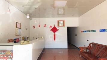 A reception area with a counter, a red decorative item on the wall, and a wooden bench.