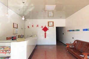 A reception area with a counter, a red decorative item on the wall, and a wooden bench.