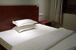A neatly made bed with pillows and a wooden headboard in a hotel room.