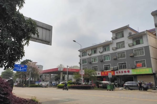 A multi-story building with commercial signage, a street with vehicles, and a clear sky.