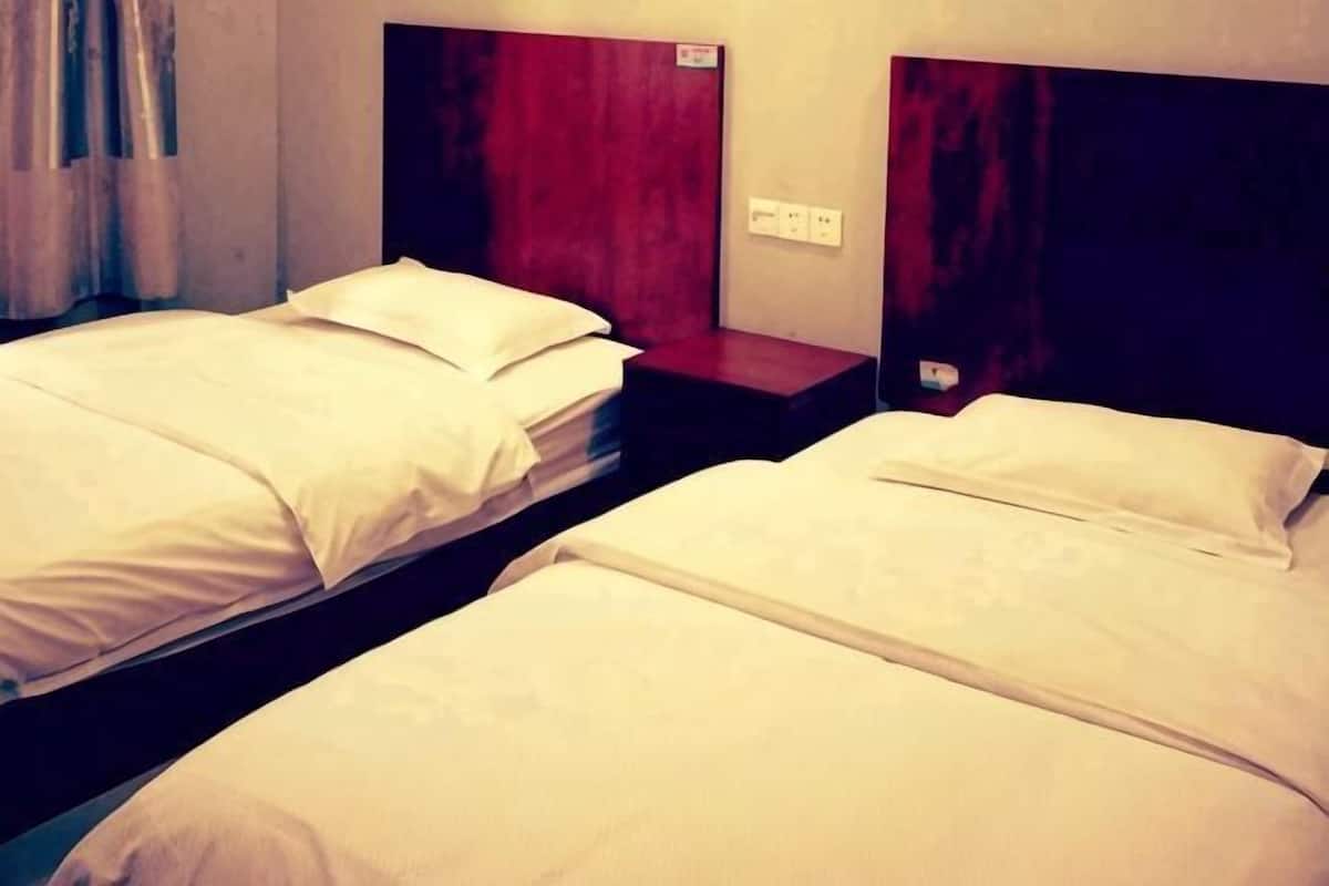 Two single beds with white linens, wooden headboards, and a red accent wall.