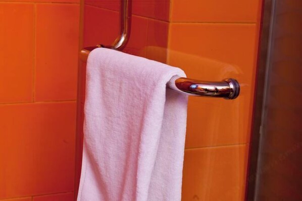 A bathroom with orange tiles and a chrome towel rack holding a white towel. - 7 Days Holiday Hotel (Guiyang Gaicha Avenue Zhongshan Middle Road) (Guiyang)