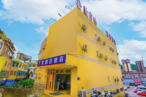 A multi-story hotel with a prominent yellow facade, a visible entrance, and a parking area in the foreground. - 7 Days Holiday Hotel (Guiyang Gaicha Avenue Zhongshan Middle Road) (Guiyang)