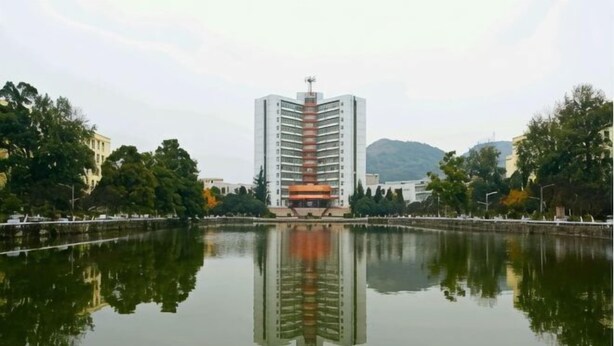 A high-rise building with a central atrium, surrounded by a calm water body reflecting the structure. - 7 Days Holiday Hotel (Guiyang Gaicha Avenue Zhongshan Middle Road) (Guiyang)