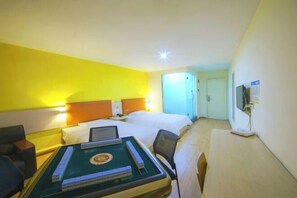 A hotel room with a bed, a desk with a computer, a chair, and a table with board games. - 7 Days Holiday Hotel (Guiyang Gaicha Avenue Zhongshan Middle Road) (Guiyang)