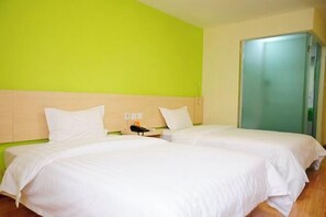 A hotel room with two beds, a green wall, and a door. - 7 Days Holiday Hotel (Guiyang Gaicha Avenue Zhongshan Middle Road) (Guiyang)