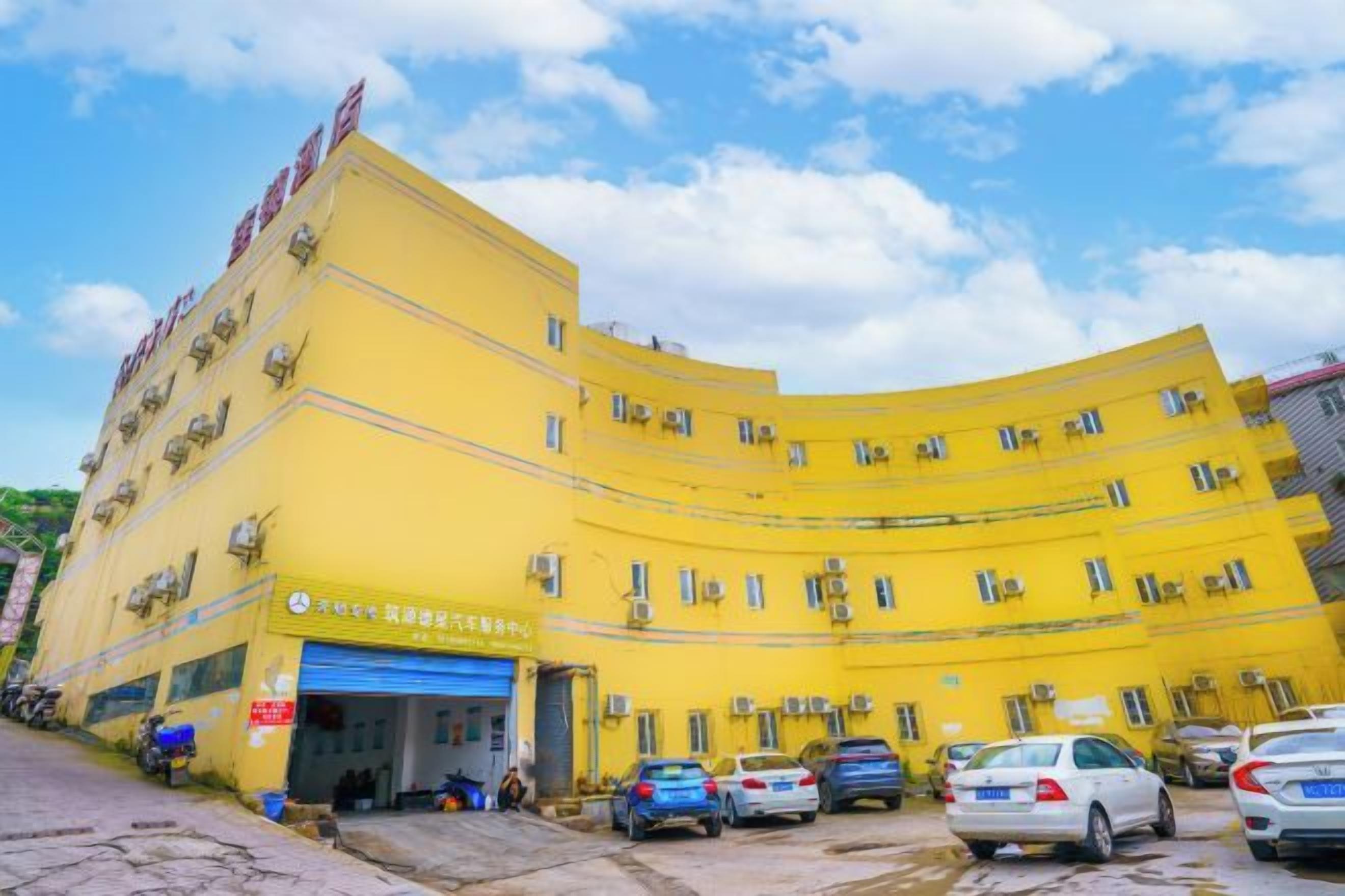 A yellow multi-story building with a blue garage door, several parked cars, and a clear sky.