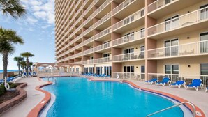 Un hotel con una piscina grande, varios balcones y vista al océano.