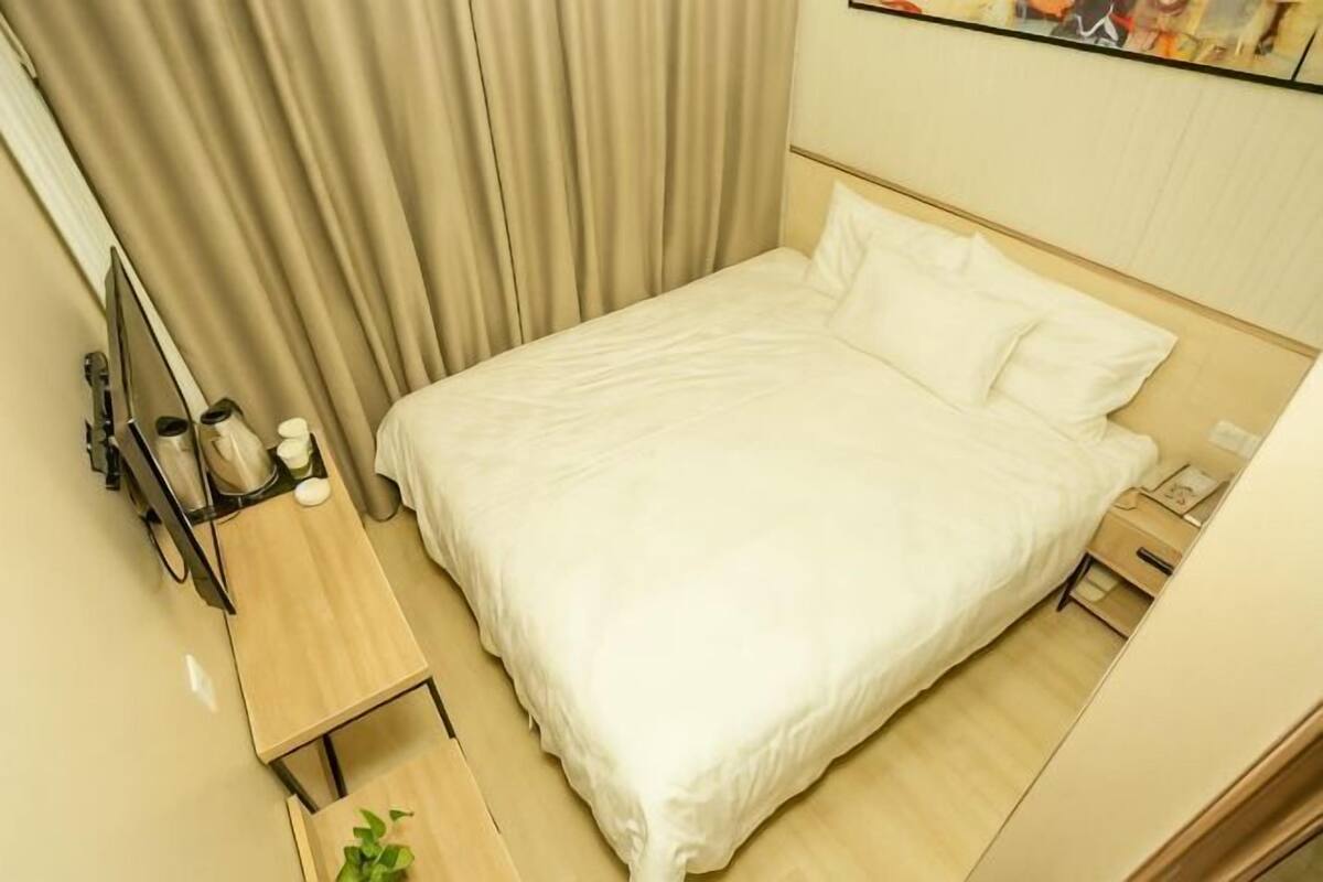 Ein ordentlich gemachtes Bett mit weißen Leinentüchern, ein Nachttisch mit Lampe und eine kleine Pflanze.