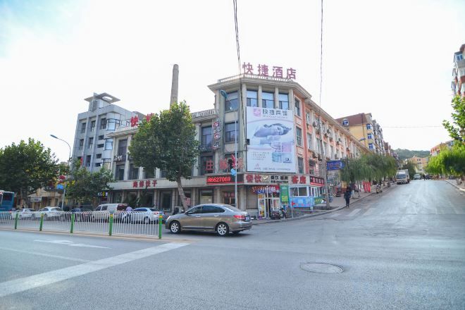 A multi-story building with commercial signage, a street view, and a clear sky.
