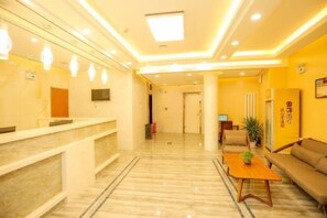A hotel lobby with a reception desk, seating area, and a television. - Pebble Motel (Jiusan Road Bus Station, Lvshun) (Dalian)