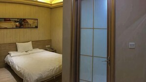 A hotel room with a bed, bedside table, and a painting on the wall. - Pebble Motel (Jiusan Road Bus Station, Lvshun) (Dalian)