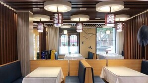 A restaurant with booths and tables, wooden paneling, and hanging lanterns. - Pebble Motel (Jiusan Road Bus Station, Lvshun) (Dalian)