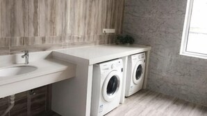A modern bathroom with a marble backsplash, a sink, and two front-loading washing machines. - Pebble Motel (Jiusan Road Bus Station, Lvshun) (Dalian)