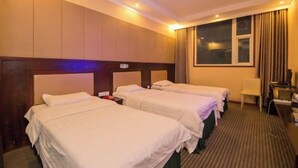 A hotel room with three single beds, a desk with a chair, a television, and a window with curtains.