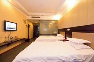 Habitación de hotel con dos camas, televisión, perchero y puerta del baño.