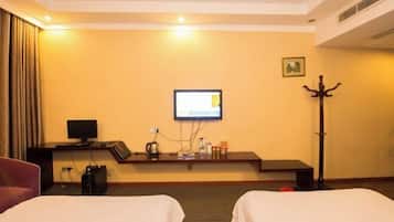 A hotel room with two beds, a desk with a computer, a television, and a coat stand.