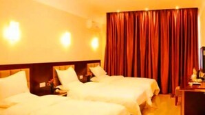 A hotel room with two beds, a desk, and a large window with curtains.