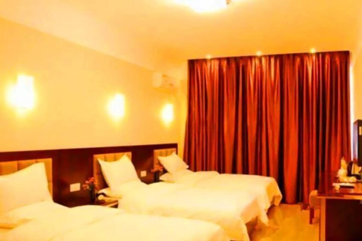 Habitación de hotel con dos camas, un escritorio y un ventanal con cortinas.