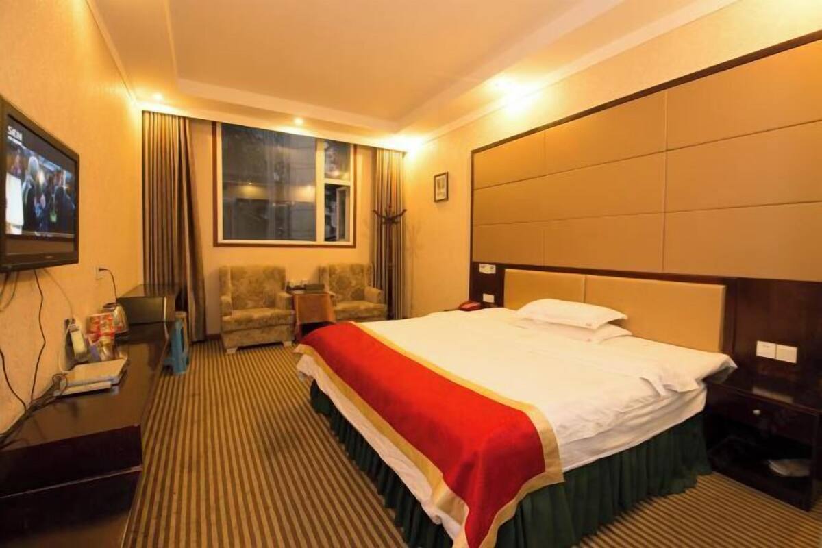Una habitación de hotel con cama, televisor, escritorio y silla.