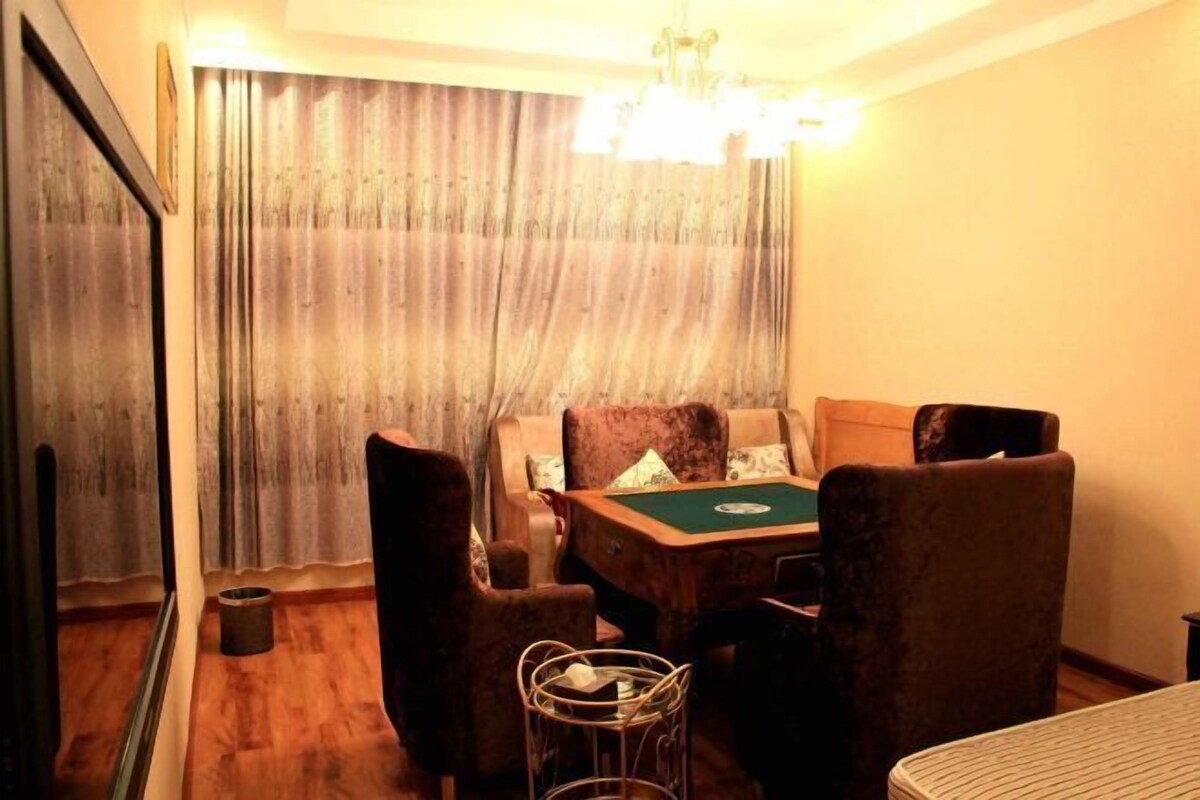 A room with a pool table, four chairs, a small table with a basket, and a mirror on the wall.