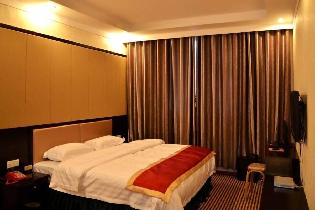 Una habitación de hotel con una cama, televisión, escritorio y una silla.