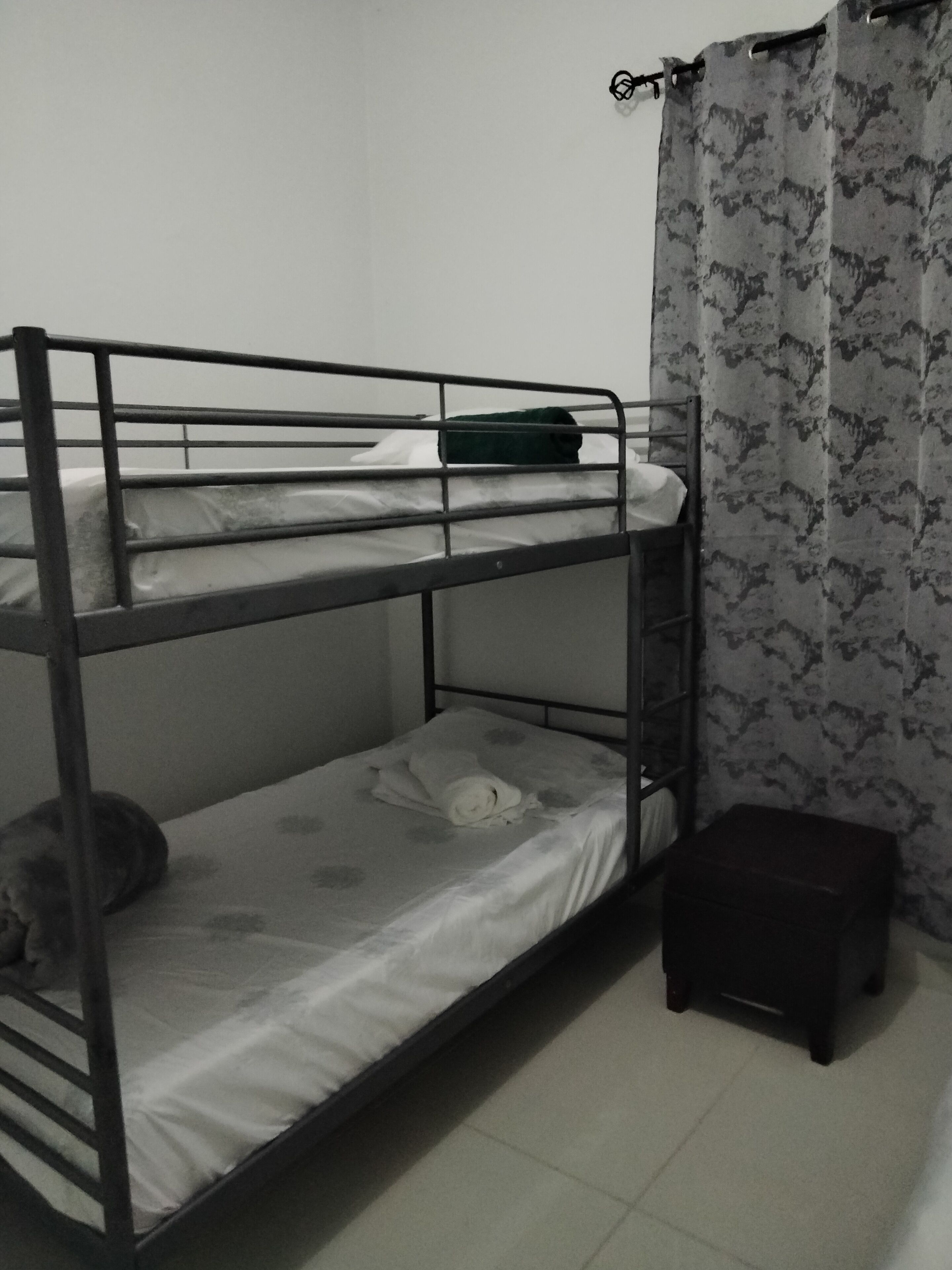 A bunk bed room with a small stool and a curtain.