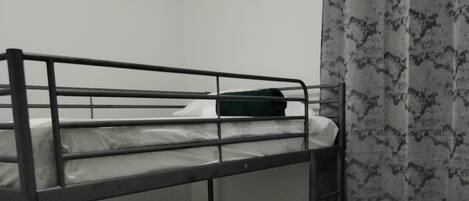 A bunk bed room with a small stool and a curtain.