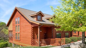Une cabane en rondins avec une véranda, une cheminée et une fenêtre.
