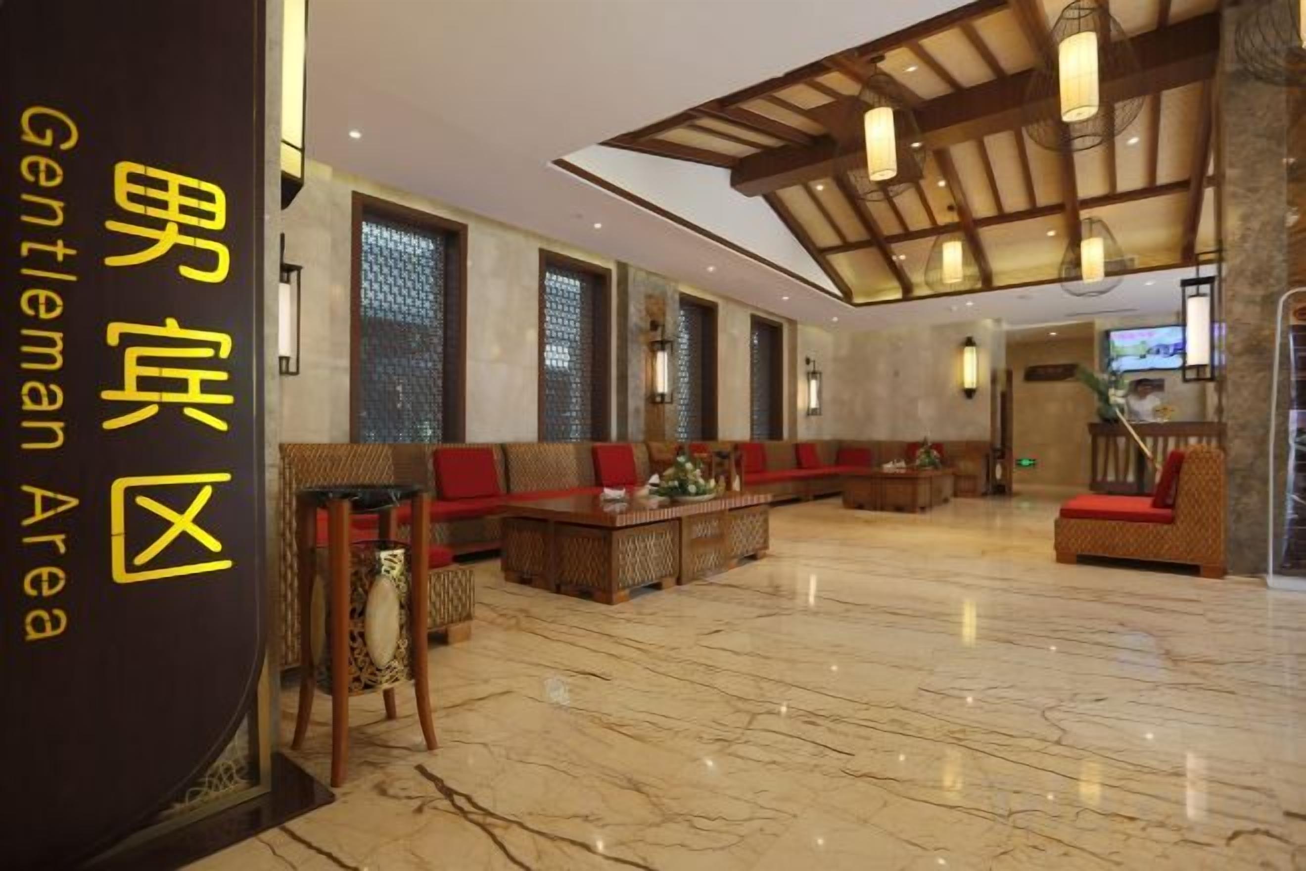 Un hall d’entrée spacieux avec un plafond haut, des espaces aménagés pour s’asseoir et un comptoir d’accueil.