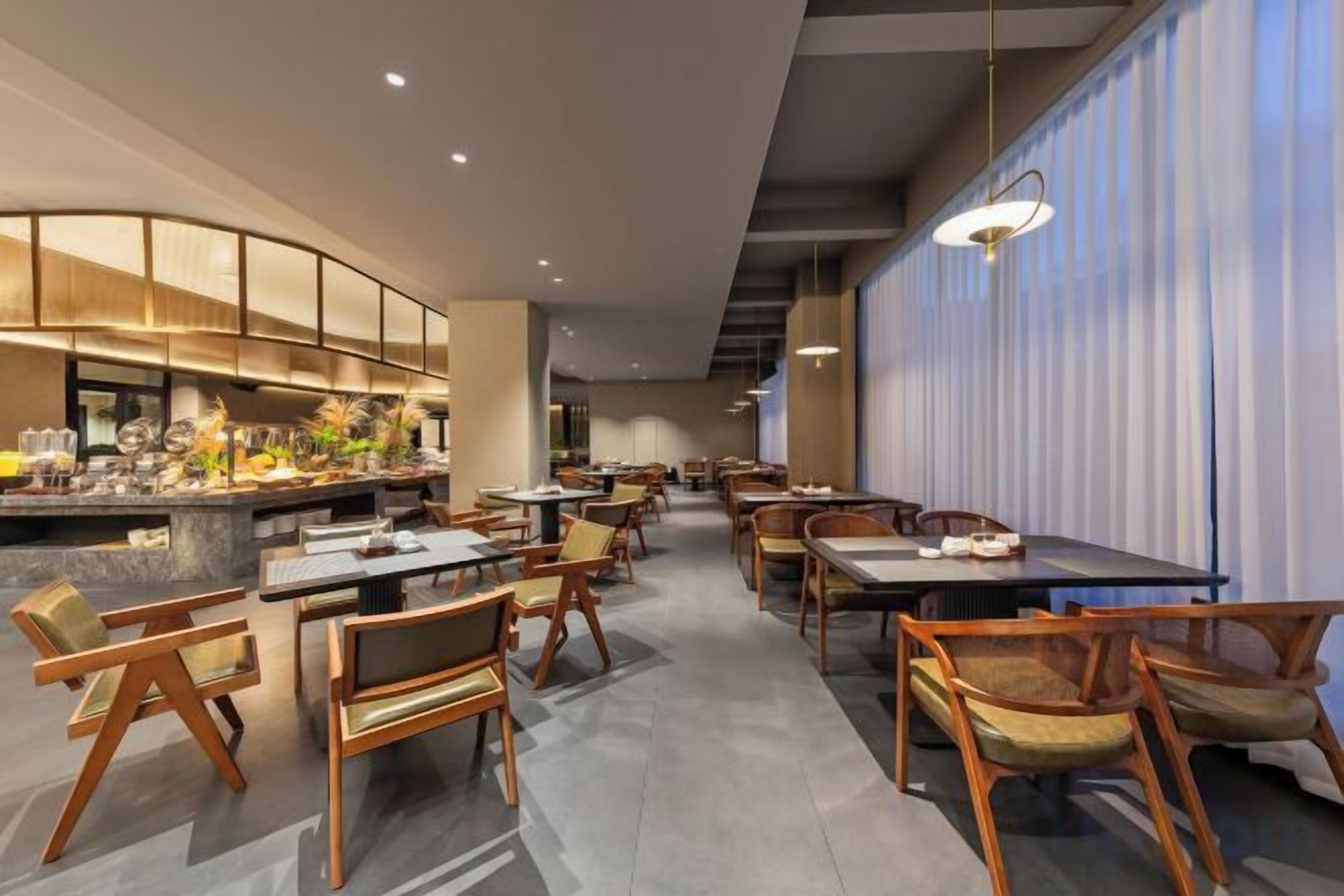 Un restaurant moderne doté d’un bar, de chaises en bois et de tables disposées pour accueillir les clients.