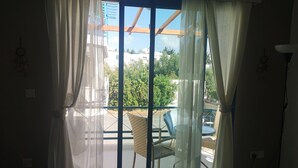 A room with a sliding glass door leading to an outdoor area with a chair and a table.