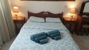 A neatly made bed with floral bedding, two bedside lamps, a wooden headboard, and a desk with a chair.