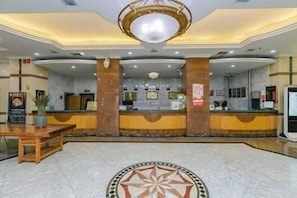 A hotel lobby with a reception desk, a chandelier, and a patterned floor. - Jinlong Hotel (Tianshui)